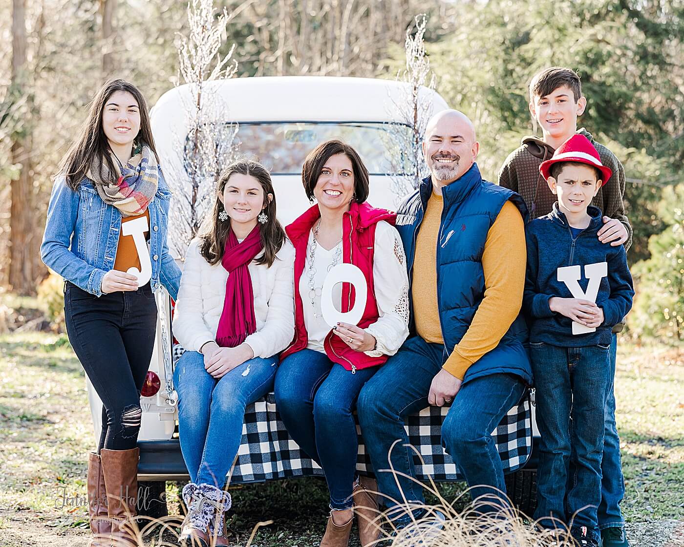 Family holding the letters to form the word “JOY” for a Christmas truck family photo session in North East, PA.