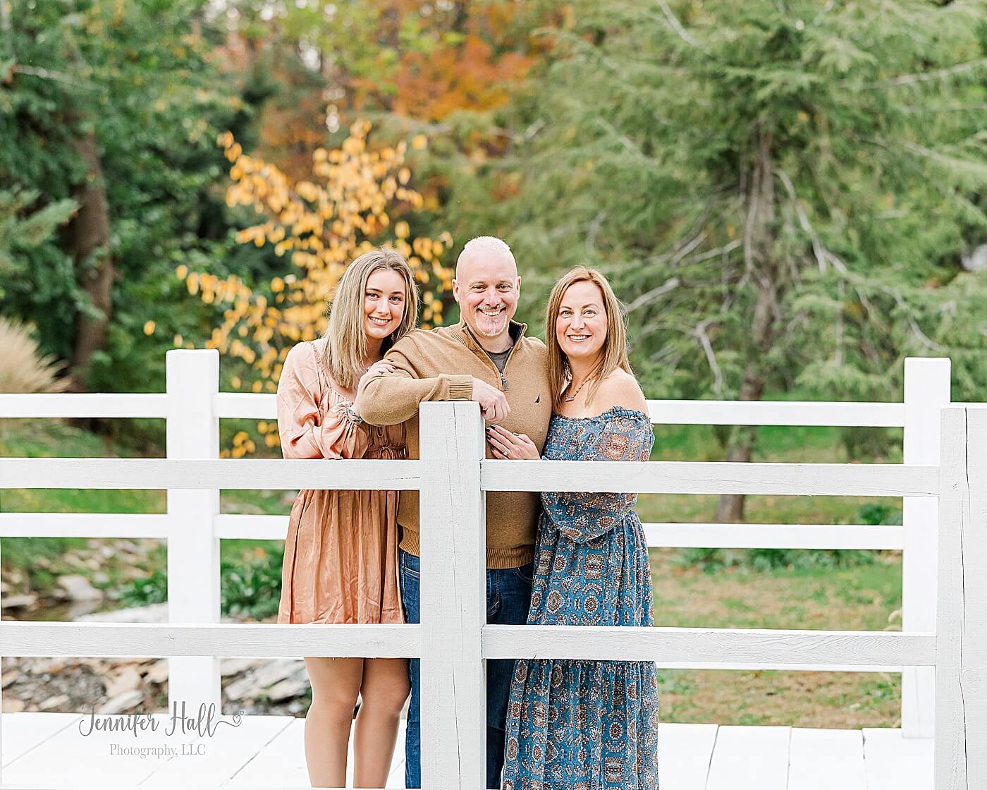 Family standing on a white bridge outdoors for a fall family photo session in North East, PA.