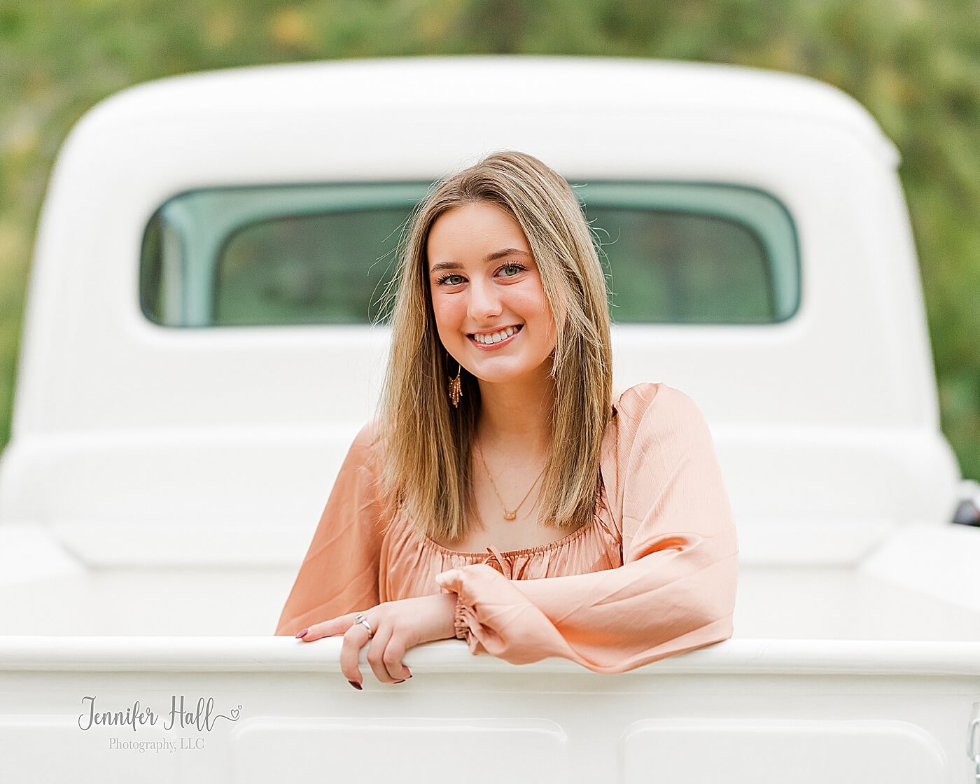 Girl sitting in the back of a vintage truck with her hand on the tailgate for a fall family photo session in North East, PA.