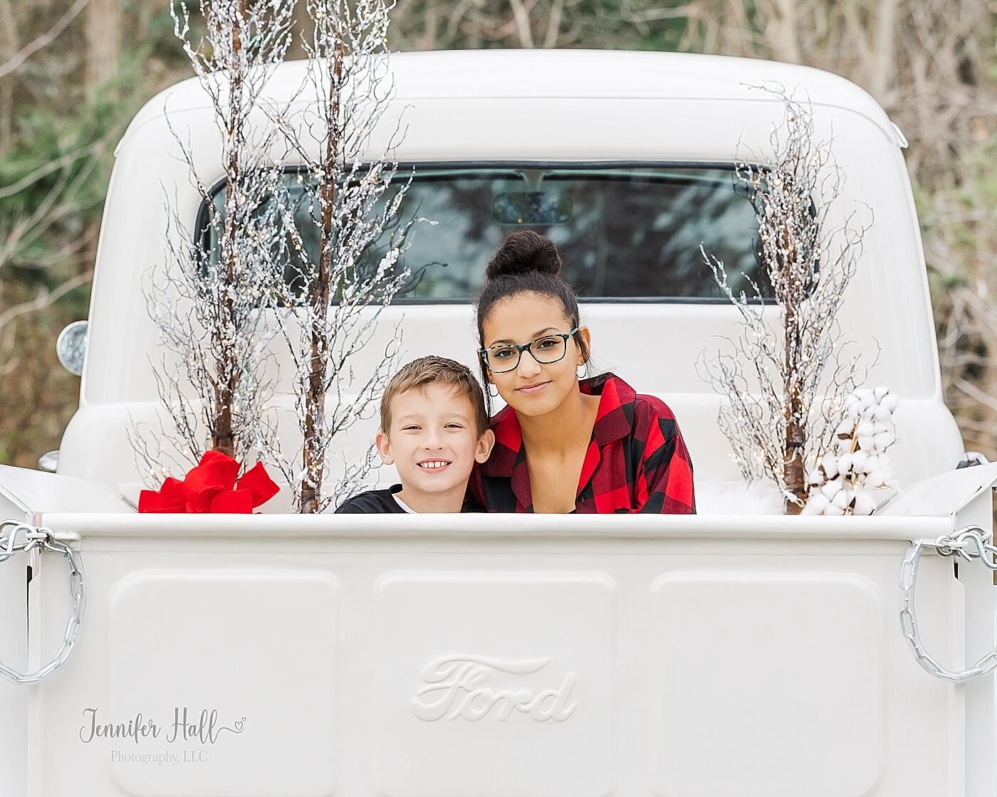 Brother and sister sitting together in the back of a white, vintage truck for Christmas truck family photos in North East, PA.