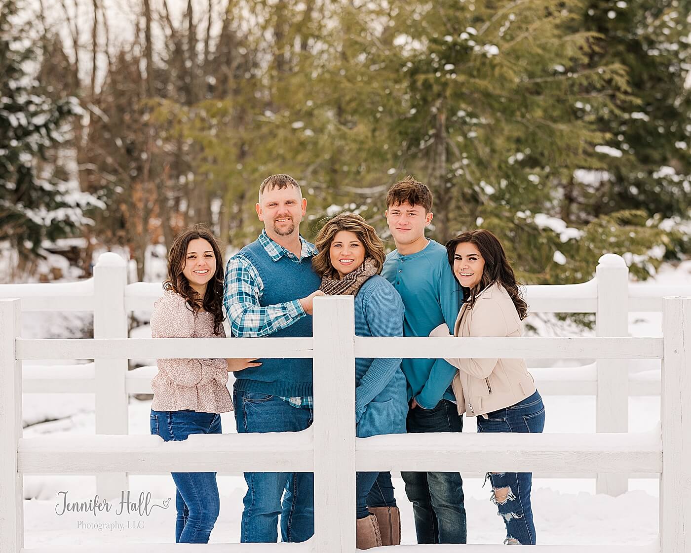 Family with blue and pink outfits standing on a white bridge in the snow near Erie, PA.