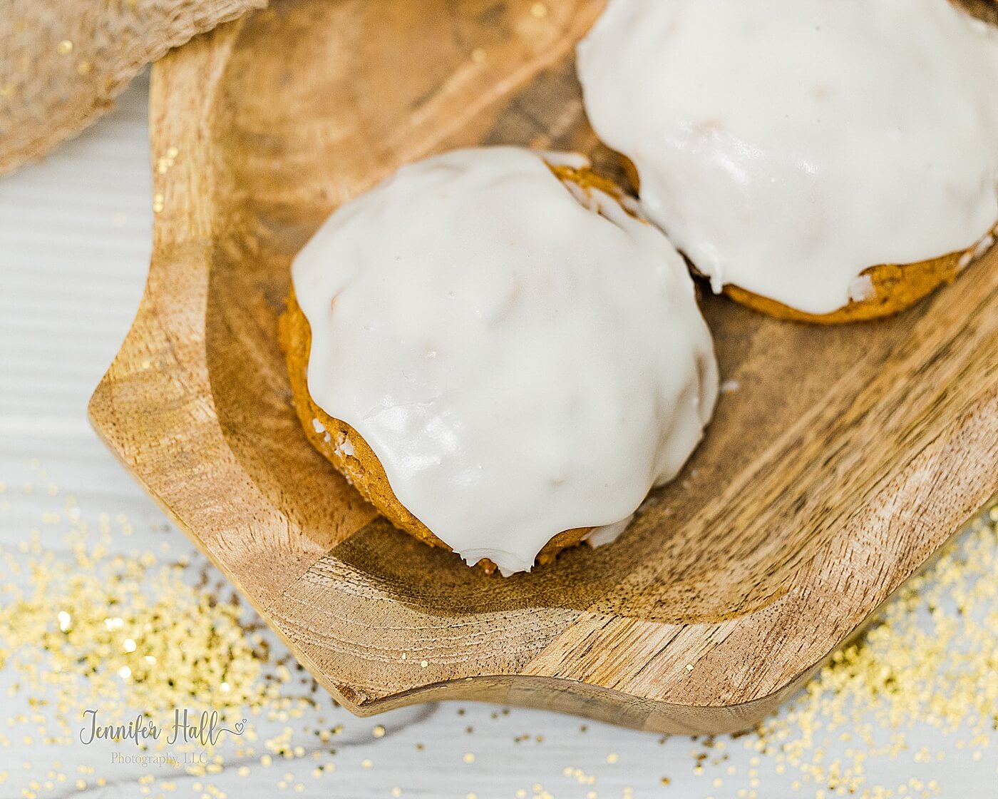 Orange pumpkin cookie on a wooden platter to show a reward a family could give their kids for listening during family photos.