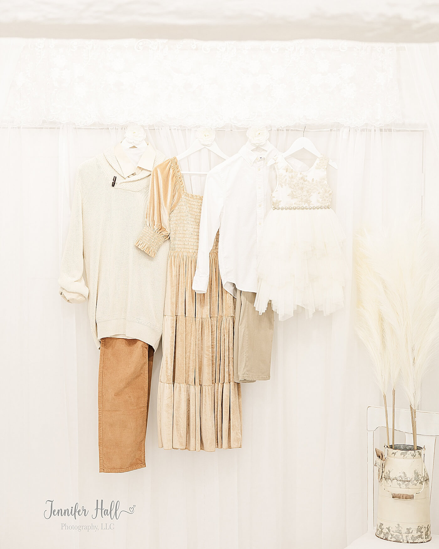 French gold dress; beige sweater with a beige dress shirt and mustard corduroys; cream dress; and a white dress shirt with tan khakis hanging on a white wall for a French gold and beige outfit color palette for fall family photos.