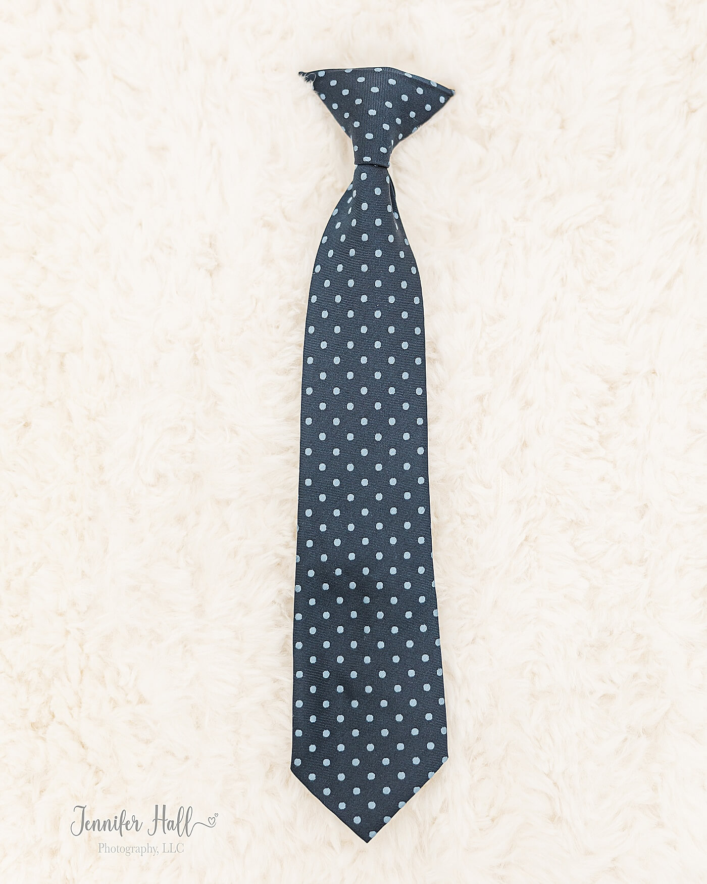 Navy tie laying on a cream blanket for older boy accessory ideas.