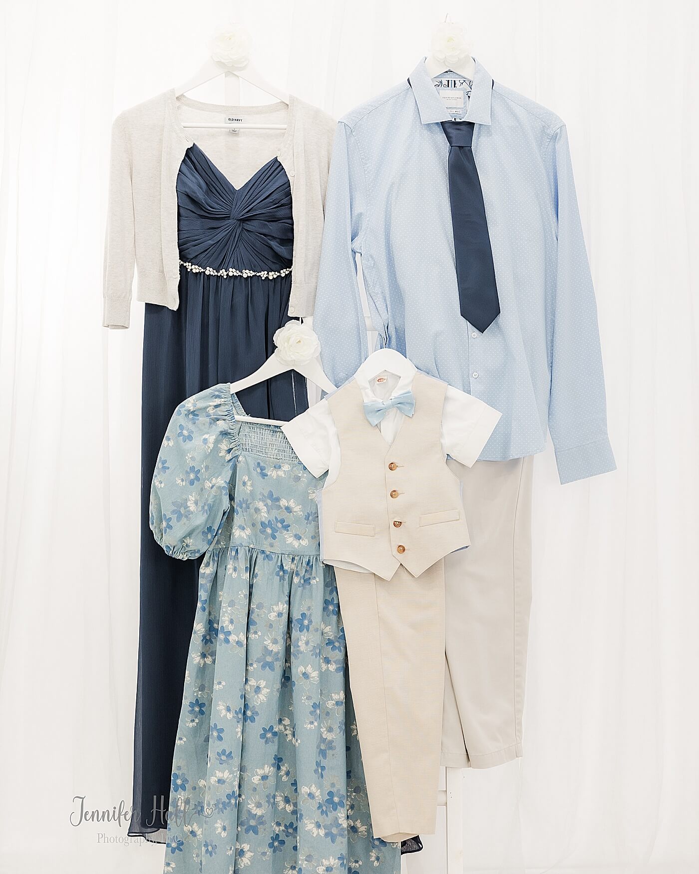 Navy dress, a light sky-blue collared shirt with beige khakis, a powder blue dress, and a beige suit vest with beige dress pants for what to wear for a family portrait session.