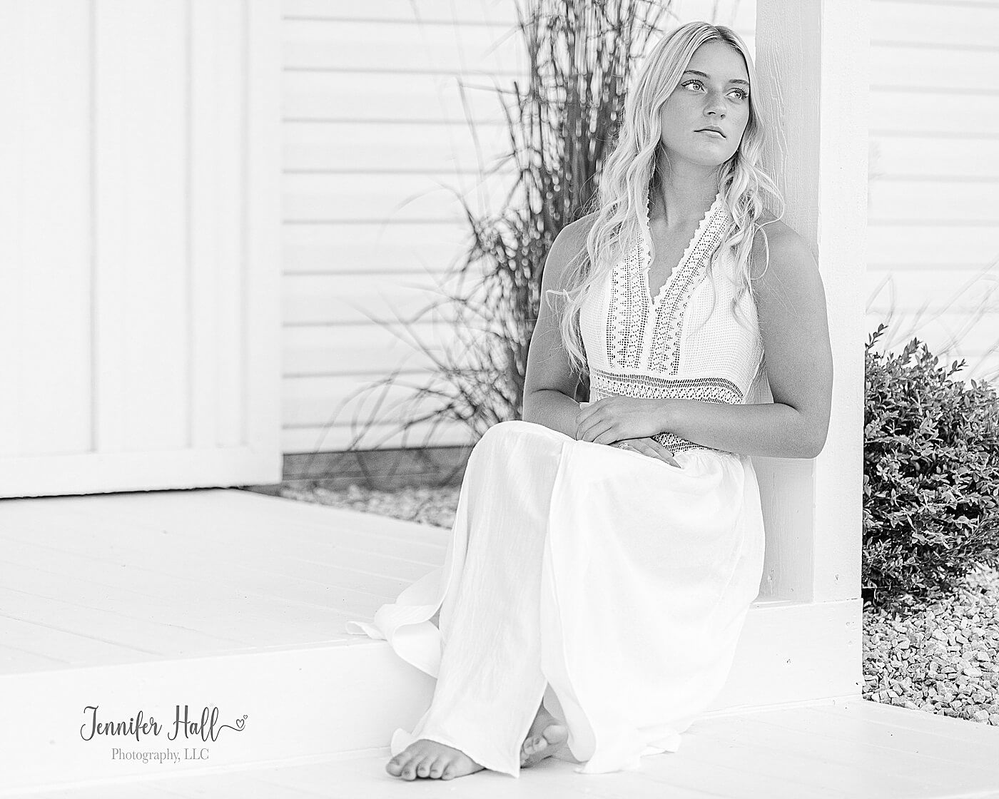 Senior girl with a long, white dress sitting on outdoors, showing teen and senior girl portrait session outfit ideas.