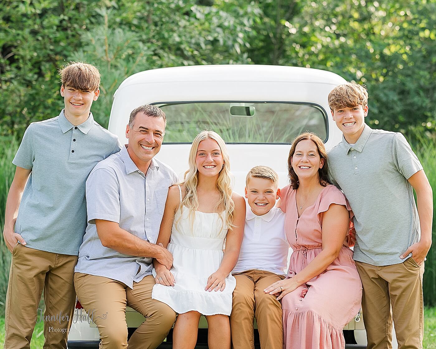 Family sitting on a white truck outdoors, showing family portrait session outfit ideas.