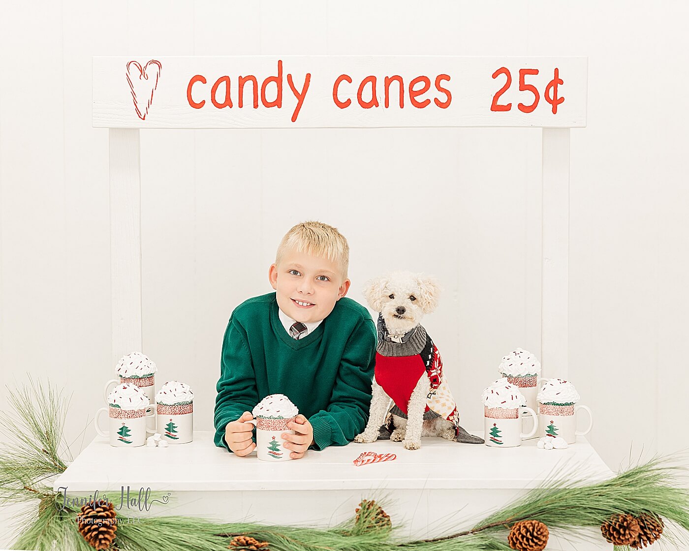 Boy holding a hot coco mug by a candy cane stand for what to wear for Christmas family photos.