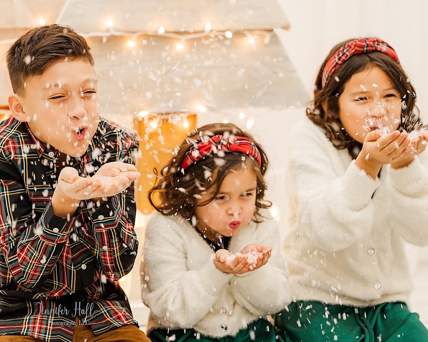 Kids blowing snow with coordinating outfits showing what to wear for Christmas family photos.