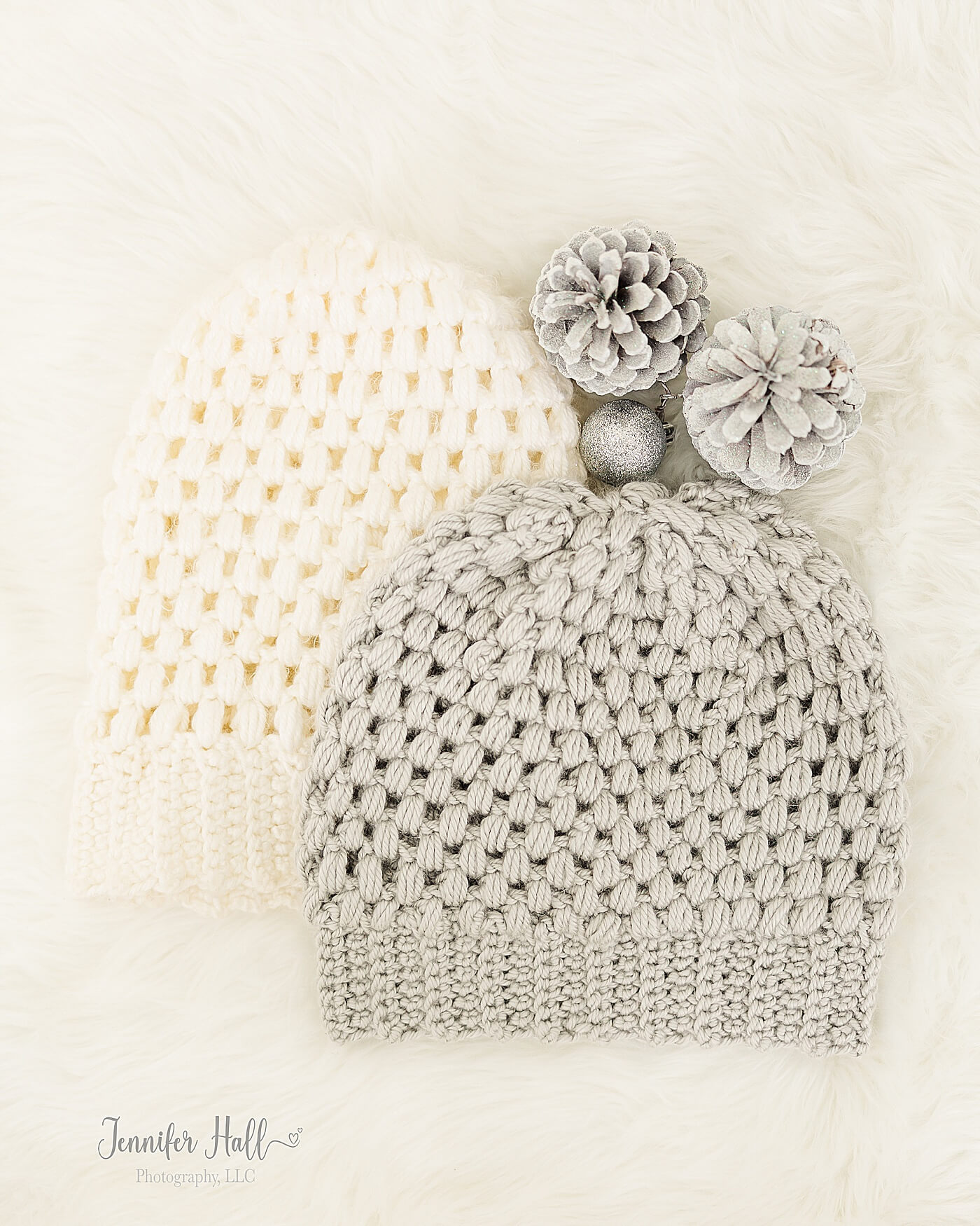 White and light silver beanies laying on a white blanket for cold-weather accessories.