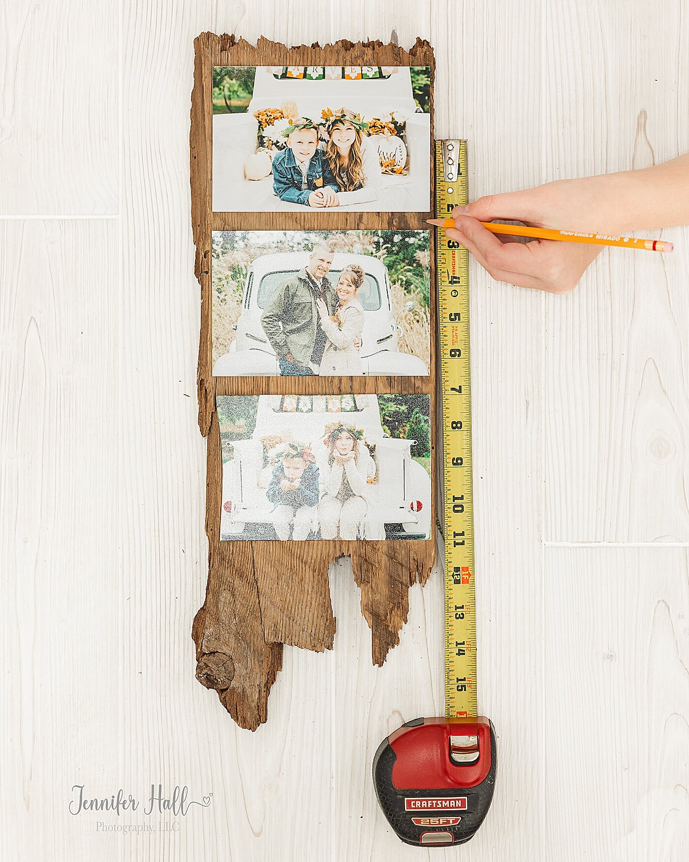 Boy measuring where photos should go on a board and marking those spots.