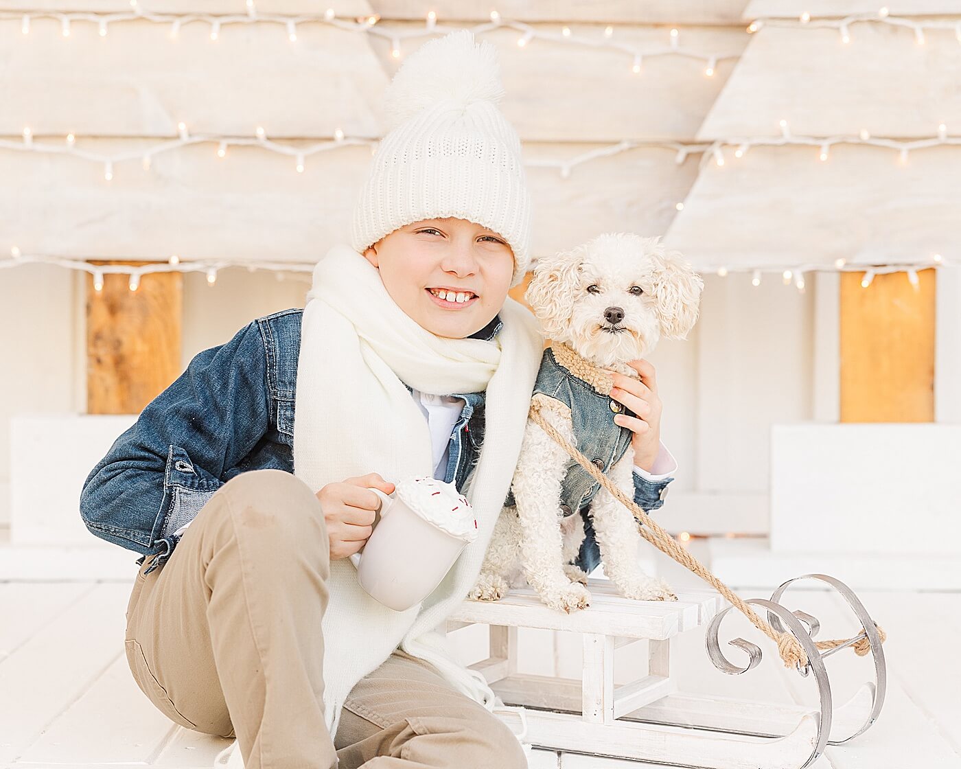 Little boy with a hot cocoa mug and sled for Christmas pictures.