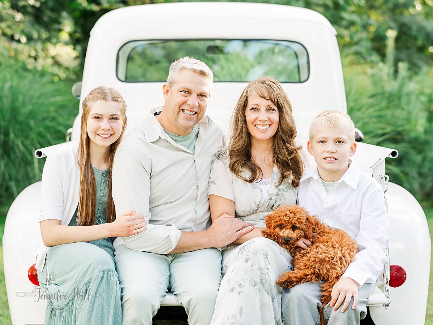 Family photographers at Jennifer Hall Photography, LLC sitting on their white truck, named “Matthew.”