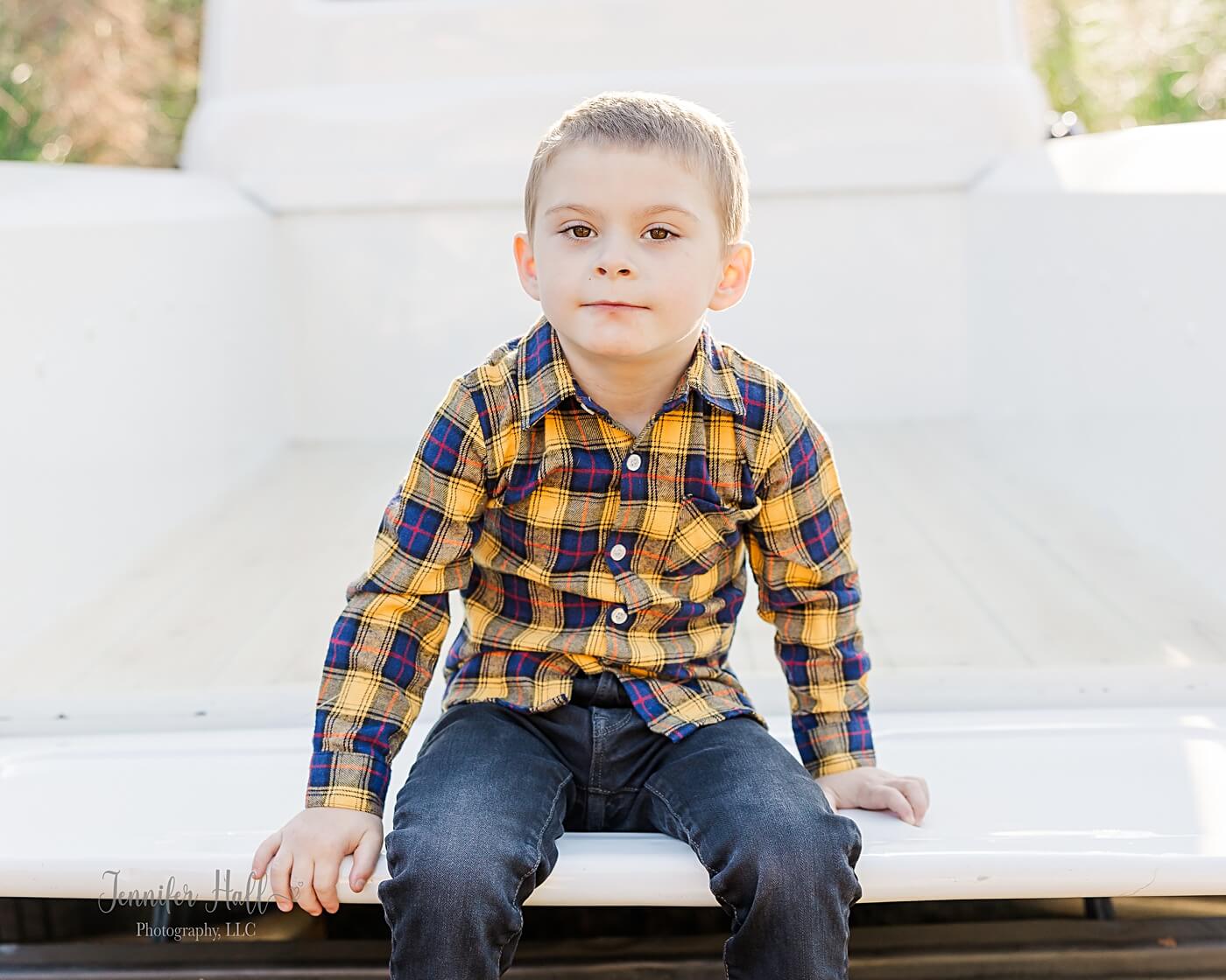 Little boy sitting on the tailgate of a white, vintage truck.