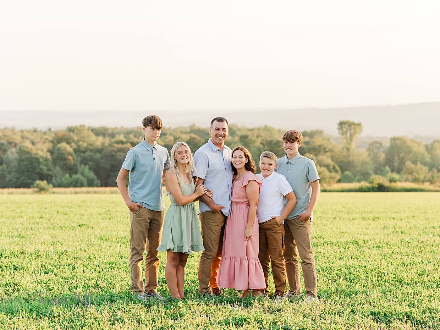 Family standing together in a grassy field outdoors.