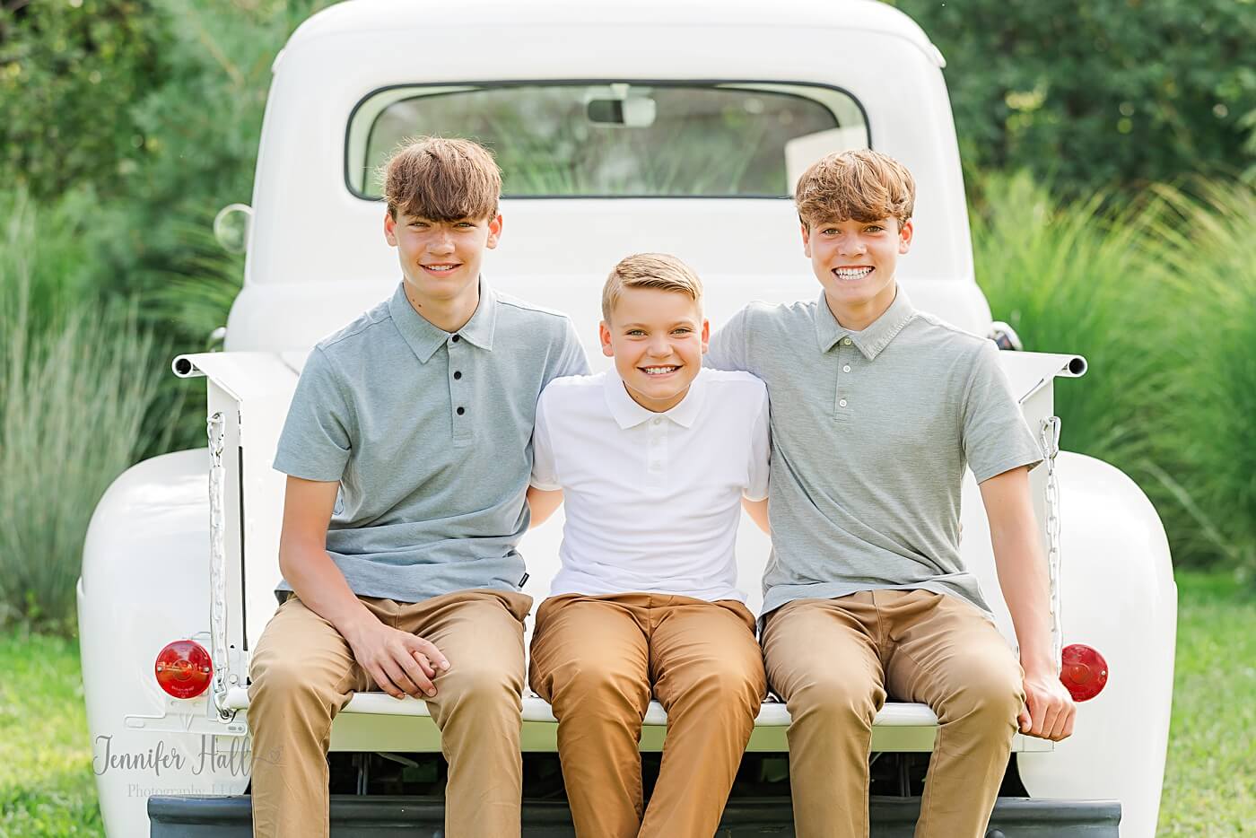 Boys with light outfit colors (light blue, white, and gray) sitting together in a truck.