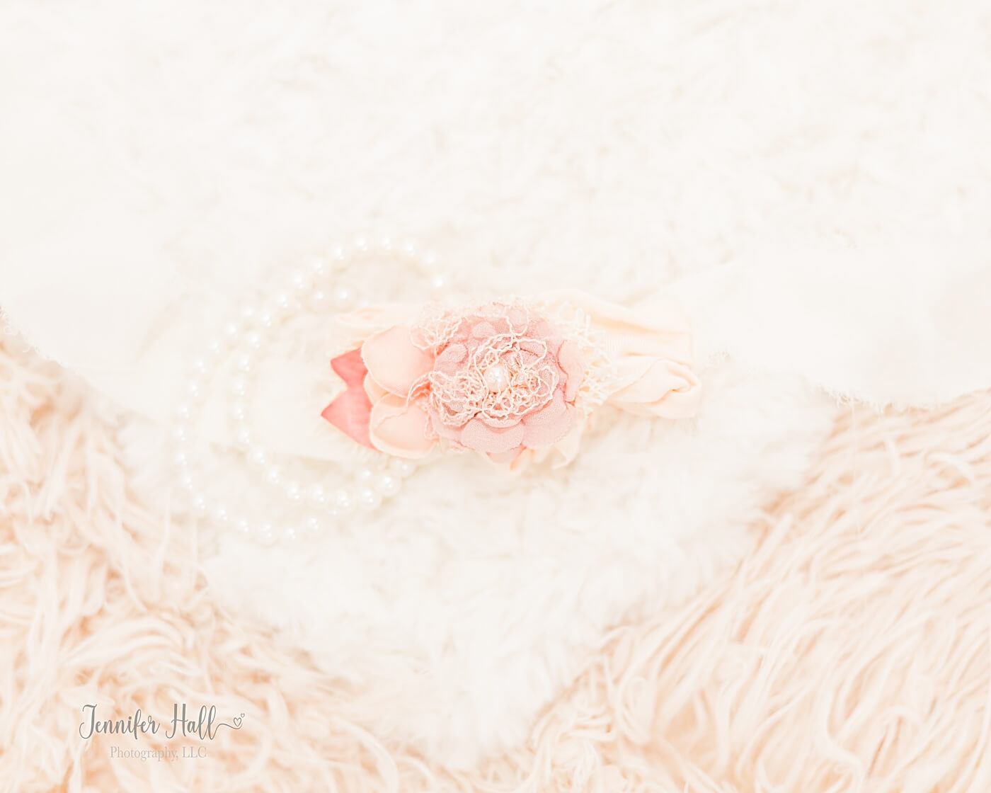 Little girls’ white bracelets and a blush flower headband together.