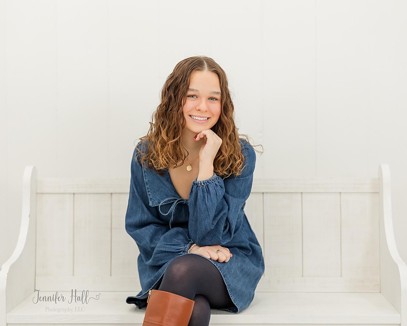 Girl sitting on a white wooden bench indoors.